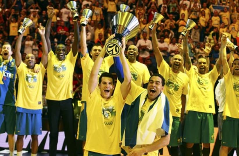 Maccabi Tel Aviv's Guy Pnini (L) and David Blu hold the trophy as they celebrate with teammates after winning their Euroleague Final Four final basketball game against Real Madrid, in Milan May 18, 2014. (photo credit: REUTERS)