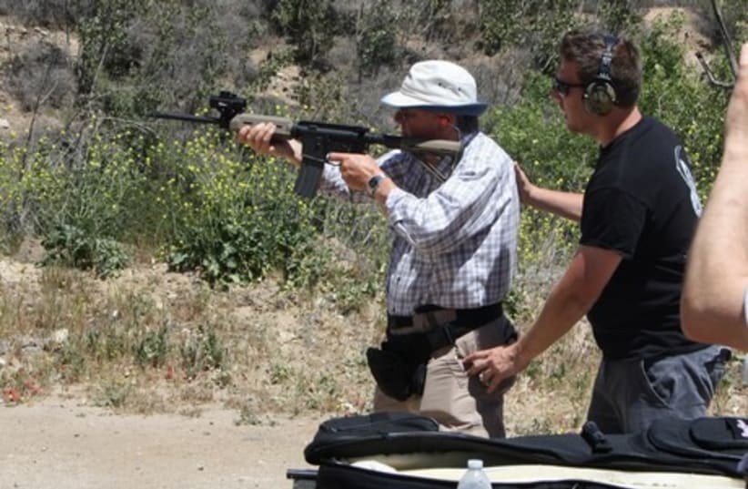 Itamar Gelbman adjusts survivor Les Hajnal's stance as he fires an AR15 rifle, during a shooting class for American Children of Jewish Holocaust Survivors. (photo credit: ANTHONY WEISS)