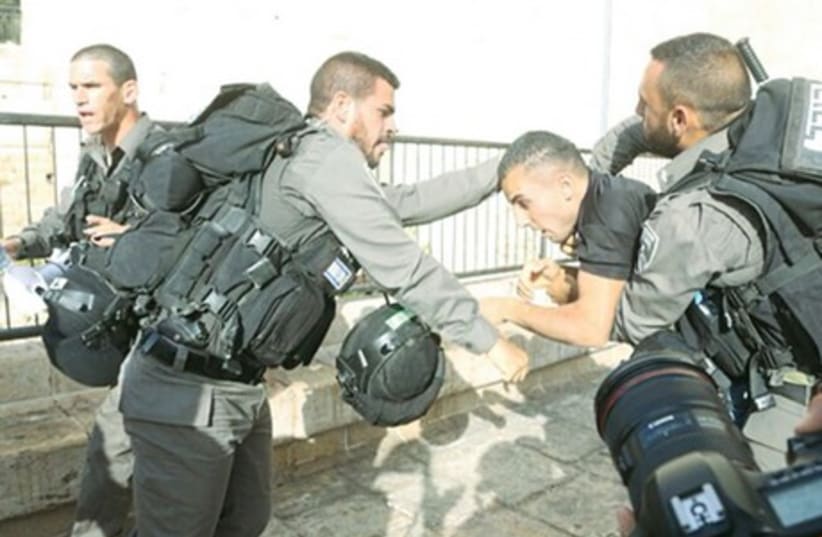 BORDER POLICE detain a Palestinian during clashes at a protest against the Jerusalem Day march, near Damascus Gate in the capital’s Old City. Nine Palestinians were detained on suspicion of throwing stones at policemen and march participants (photo credit: MARC ISRAEL SELLEM)