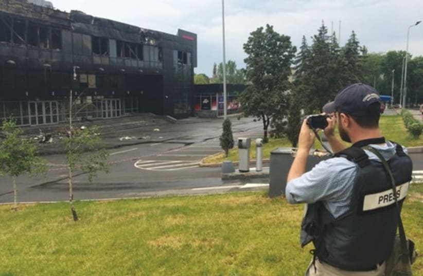 ‘POST’ REPORTER Sam Sokol takes a picture of a building damaged in a battle in separatist-controlled Donetsk yesterday. (photo credit: Courtesy)