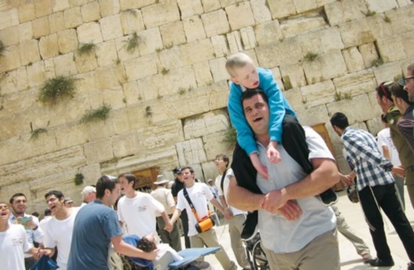 AMOS BUCHNIK, 23, carries Chaim at the Western Wall. As a volunteer, Buchnik has been with Chaim for the last five years. (photo credit: Courtesy)