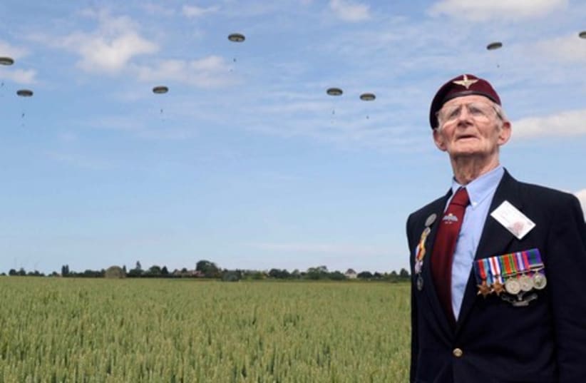 British World War II veteran Frederick Glover poses for a photograph as soldiers parachute down during a D-Day commemoration paratroopers launch event in Ranville, northern France, on June 5, 2014. (photo credit: REUTERS)