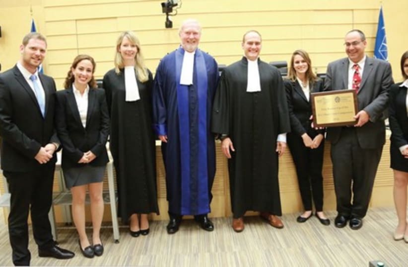 ICC JUDGE Howard Morrison (in blue), coach Dr. Rotem Giladi (holding the award) and the Israeli team pose in The Hague.   (photo credit: ICC)