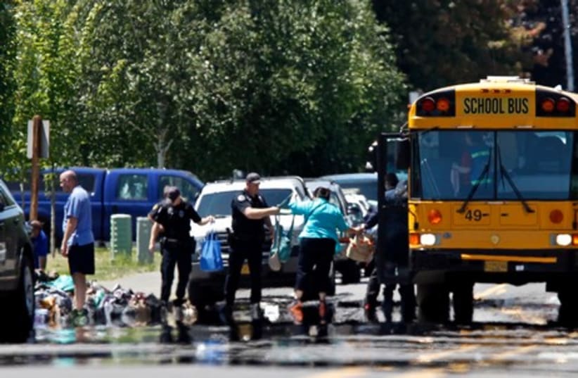 Police transfer student backpacks into a school bus after a shooting at Reynolds High School in Troutdale, Oregon June 10, 2014 (photo credit: REUTERS)