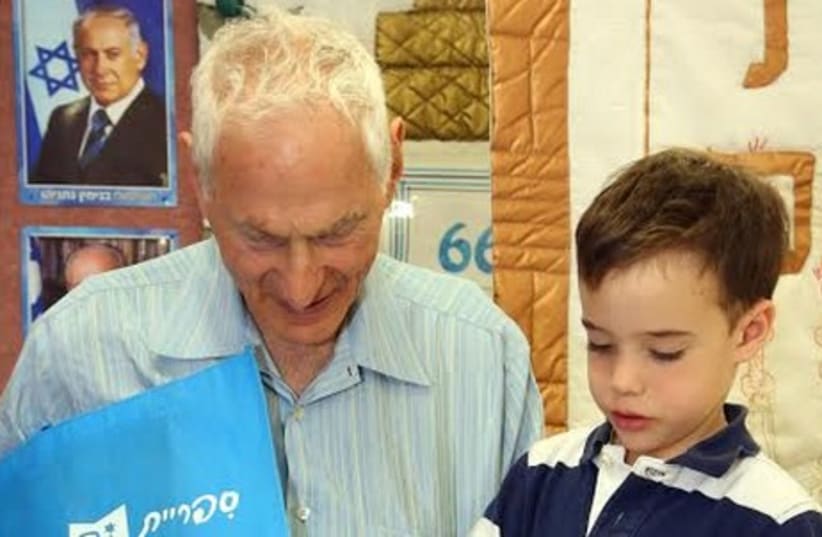Harold Grinspoon distributes the 5 millionth book to a young preschool boy (photo credit: SASSON TIRAM)