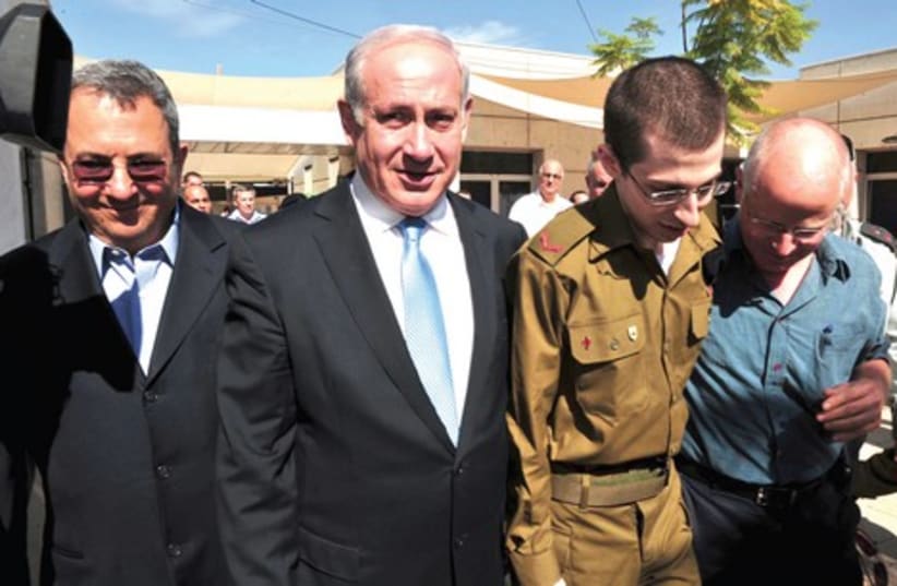 Gilad Schalit walks with his father, Noam, alongside Prime Minister Benjamin Netanyahu and Defense Minister Ehud Barak at an official welcome at Tel Nof air base, October 18, 2011 (photo credit: REUTERS)