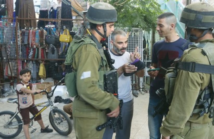 IDF soldiers speak with Palestinians in Hebron last week during the manhunt for three kidnapped Israeli youth. (photo credit: MARC ISRAEL SELLEM/THE JERUSALEM POST)