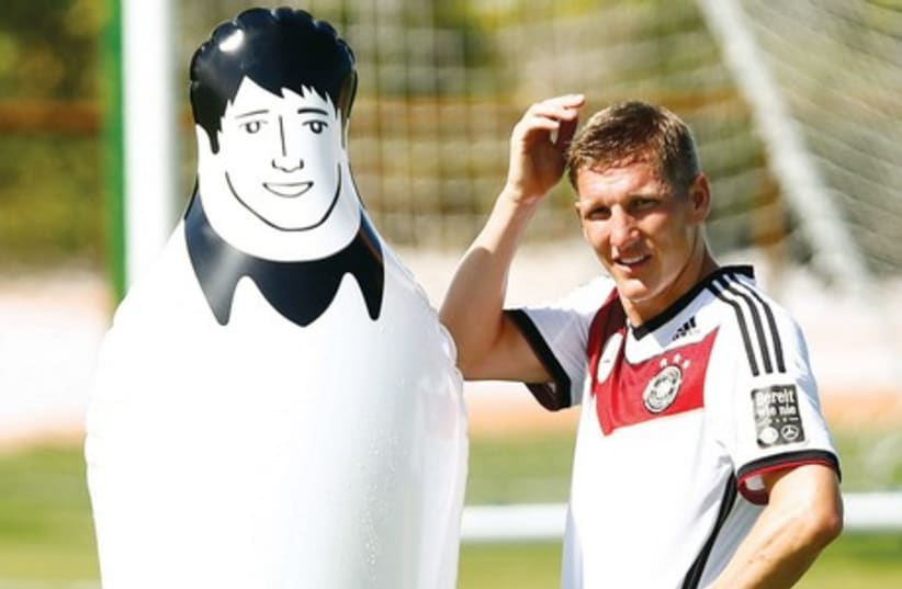 Germany's national soccer player Bastian Schweinsteiger stands beside a dummy during a World Cup 2014 training session in the village of Santo Andre, north of Porto Seguro, on Tuesday. (photo credit: REUTERS)
