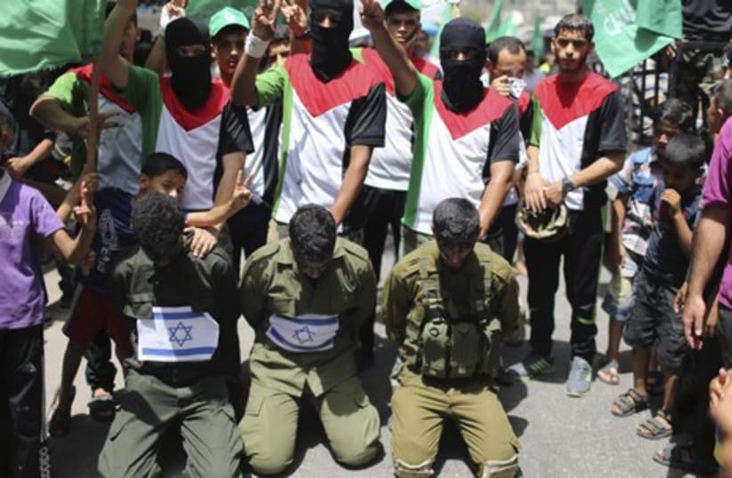 Hamas supporters enact a scene simulating the abduction of three Israeli soldiers during a rally in the Gaza Strip, June 20, 2014.  (photo credit: REUTERS)