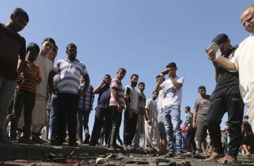 Palestinians survey the wreckage of an IAF strike that killed two terrorists in Gaza. (photo credit: REUTERS)