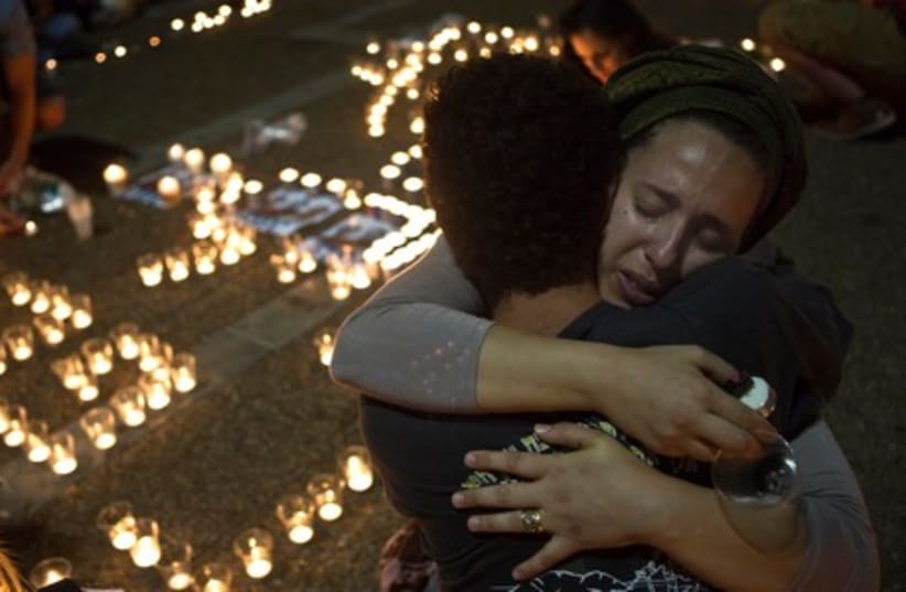 Israeli women hug each other as people light candles in Tel Aviv's Rabin Square as they mourn the death of three teenagers who were abducted, June 30, 2014.  (photo credit: REUTERS)