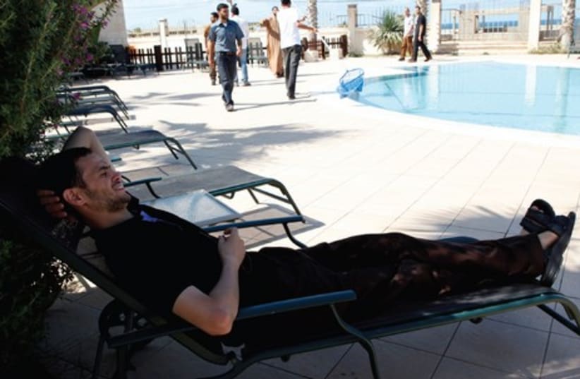 A FORMER Palestinian prisoner released as part of a deal, relaxes by a pool in Gaza in 2011. The author wonders whether prison conditions are much worse (photo credit: REUTERS)
