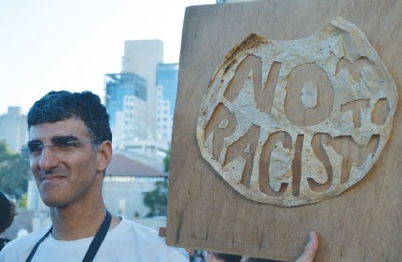 Peace protester holds "no racism" sign in Jerusalem (photo credit: LIA KAMANA)