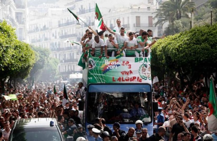 Algeria's soccer players (on bus) are welcomed by fans in downtown Algiers, after returning from the 2014 World Cup soccer tournament, July 2, 2014 (photo credit: REUTERS)