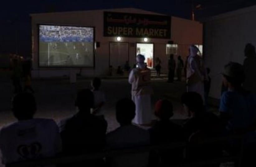 UAE Red Crescent members and Syrian refugees gather round a large screen to watch a World Cup soccer match.  (photo credit: REUTERS)