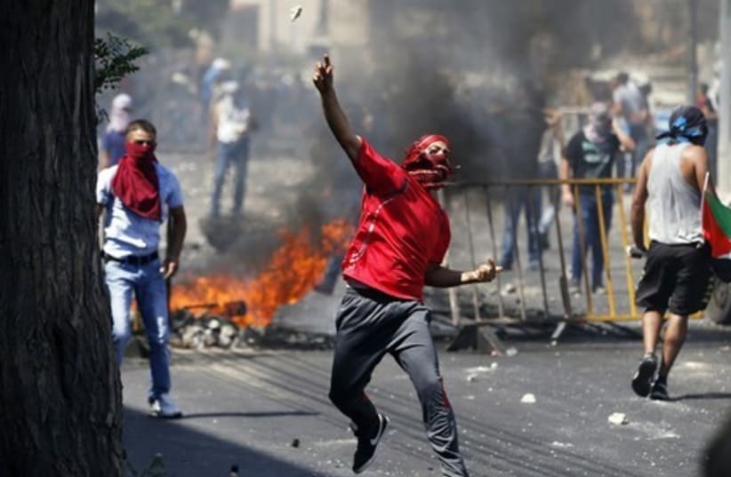 A Palestinian hurls a rock at police in the Wadi al-Joz section of east Jerusalem. (photo credit: REUTERS)