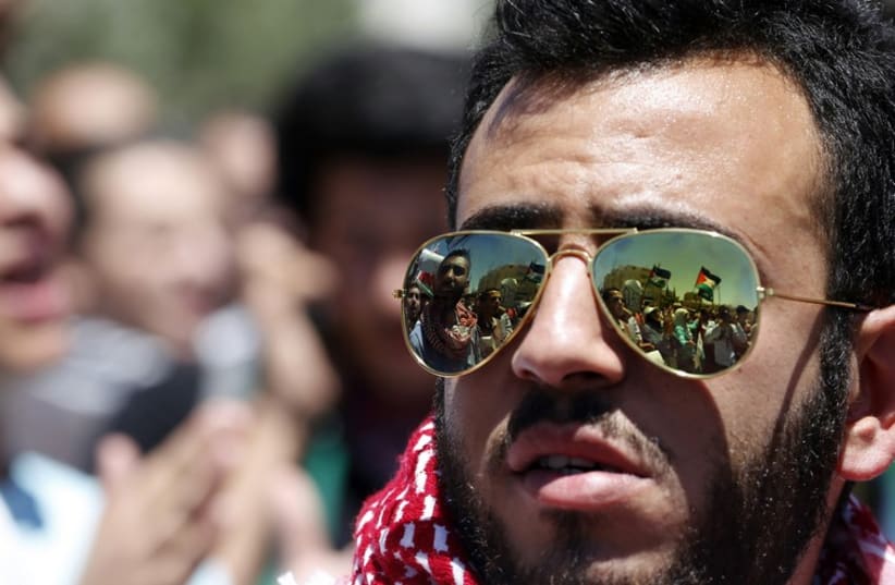 Protesters holding Palestinian flags and shouting anti-Israel slogans are reflected in a man's sunglasses during a protest near the Israeli embassy in Amman. (photo credit: REUTERS)