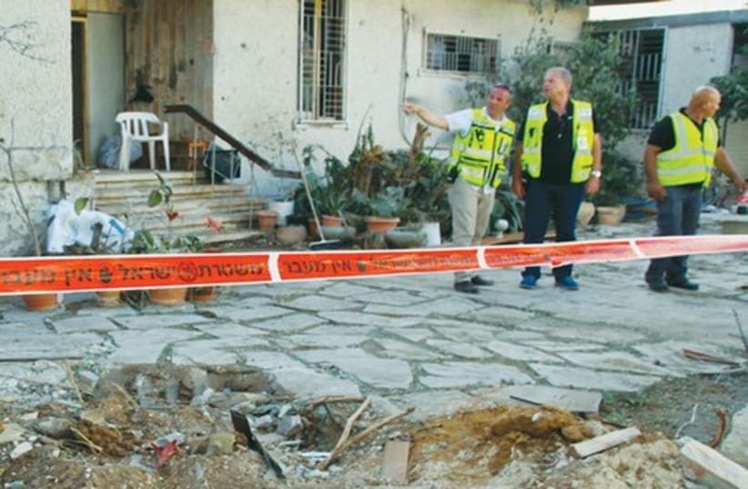 Ashdod Police officers stand in a front yard hit by a Hamas rocket. (photo credit: TOVAH LAZAROFF)