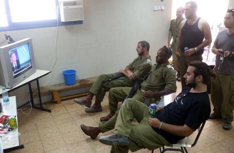 IDF RESERVISTS watch television in a Kiryat Gat community center as they wait for orders. (photo credit: MARC ISRAEL SELLEM/THE JERUSALEM POST)