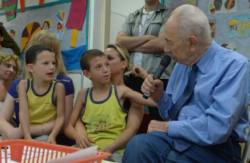 Former president Shimon Peres speaking with children and parents at Kibbutz Zikim. (photo credit: GPO)