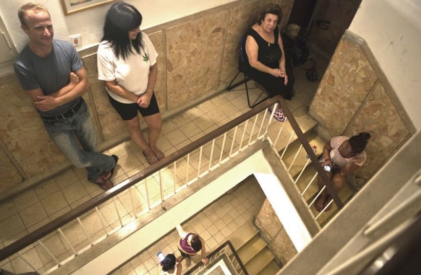 Residents take cover in the stairwell of their building during a rocket attack on Tel Aviv (photo credit: NIR ELIAS / REUTERS)