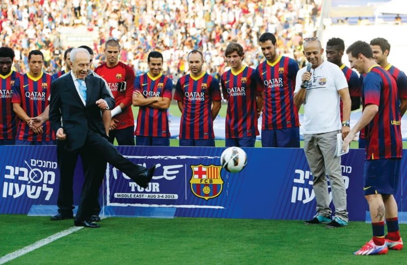 President Shimon Peres kicks the ball to Barcelona’s Lionel Messi at the opening of a soccer clinic with Arab and Jewish children at Bloomfield Stadium in Tel Aviv in August 2013. (photo credit: REUTERS)