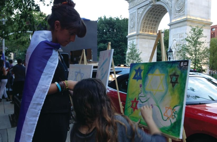 FORMER ROOMMATES Natasha Bassalian (left) and Mazal-Tov Amsellem draw on a canvas set up by Artists 4 Israel during a Thursday evening protest at Washington Square Park in New York City. (photo credit: ANNA HIATT)