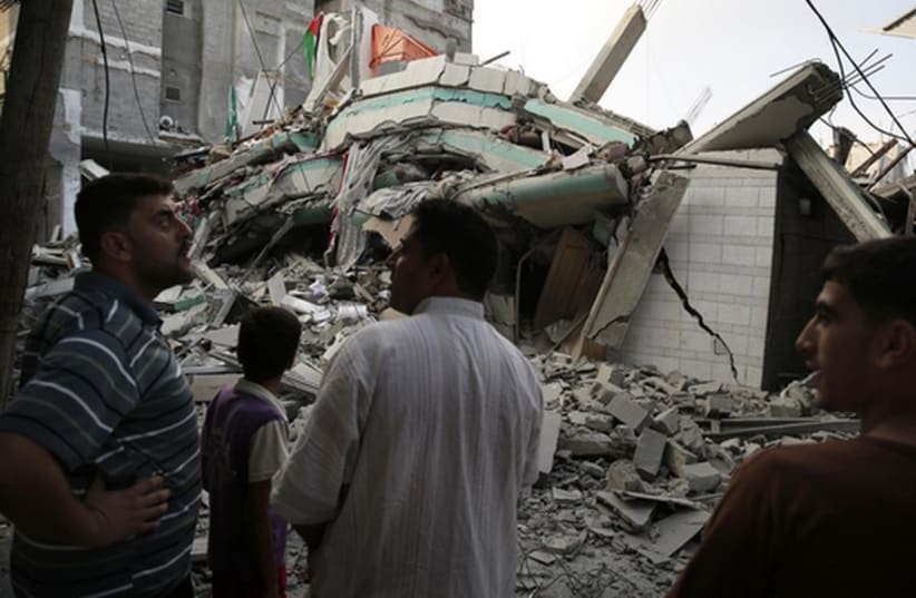 Palestinians stand by the rubble of the home of Hamas Gaza leader Ismail Haniyeh in Gaza City (photo credit: REUTERS)