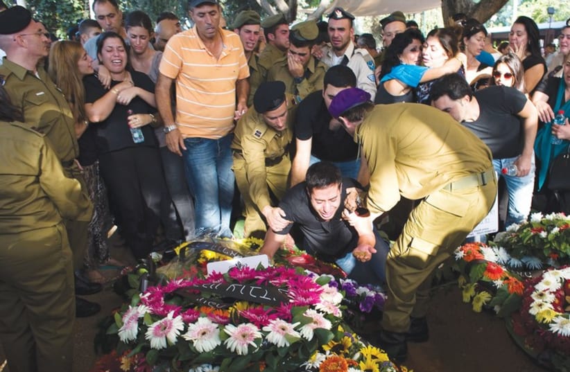 The brother of Sgt. Daniel Kedmi mourns over his grave at the Kiryat Shaul Military Cemetery. (photo credit: RONEN ZVULUN / REUTERS)