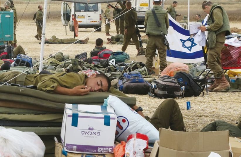 A soldier sleeps at a base camp near the border with the Gaza Strip, surrounded by packages donated by citizens. (photo credit: MARC ISRAEL SELLEM/THE JERUSALEM POST)