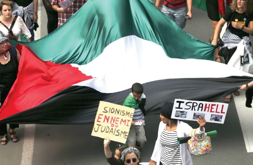 Demonstrators in Brussels hold a giant Palestinian flag and anti-Israel signs (photo credit: REUTERS/FRANCOIS LENOIR)