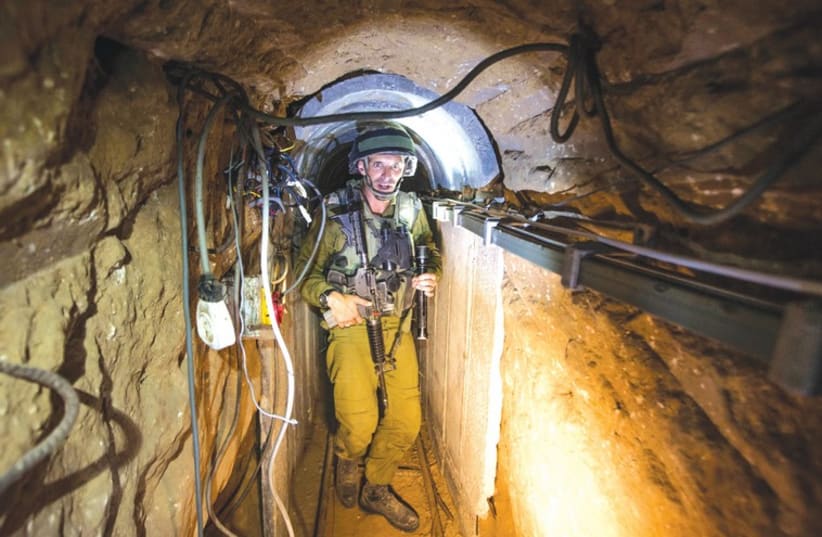 An IDF soldier traverses a tunnel used by Hamas gunmen for cross-border attacks (photo credit: REUTERS)
