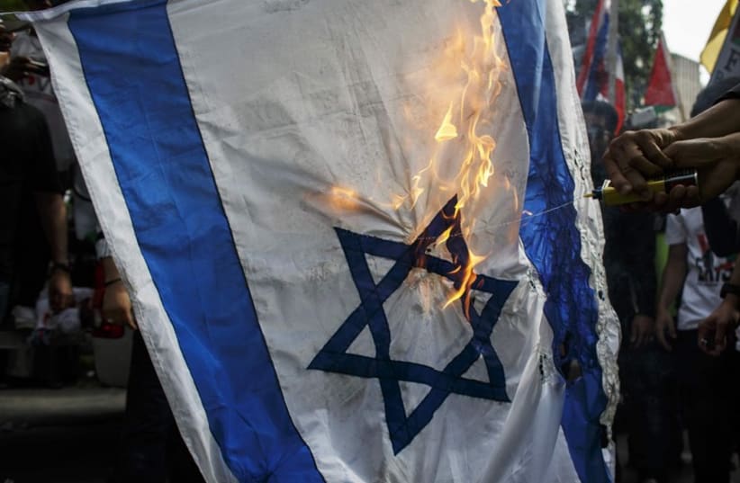 Demonstrators burn an Israeli national flag during an anti-Israel protest (photo credit: REUTERS)
