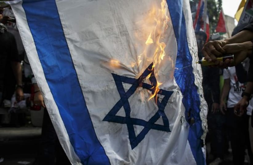 Demonstrators burn an Israeli national flag during an anti-Israel protest (photo credit: REUTERS)