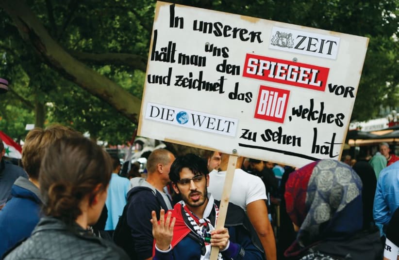 A demonstrator holds a placard during a Muslim protest in Berlin last week against the Israeli assault on the Gaza Strip. (photo credit: REUTERS)