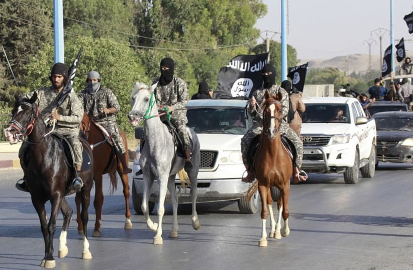 Militant Islamist fighters ride horses as they take part in a military parade along the streets of Syria's northern Raqqa province June 30, 2014. (photo credit: REUTERS)