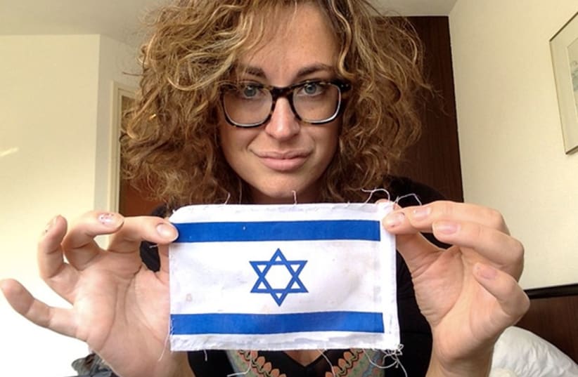 Annika Rothstein holds an Israeli flag that was ripped off her Israel-bound suitcase (photo credit: Courtesy)