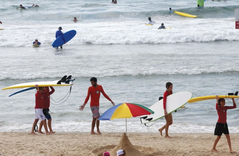 Beachgoers surf the waves in Tel Aviv last week. (photo credit: MARC ISRAEL SELLEM/THE JERUSALEM POST)