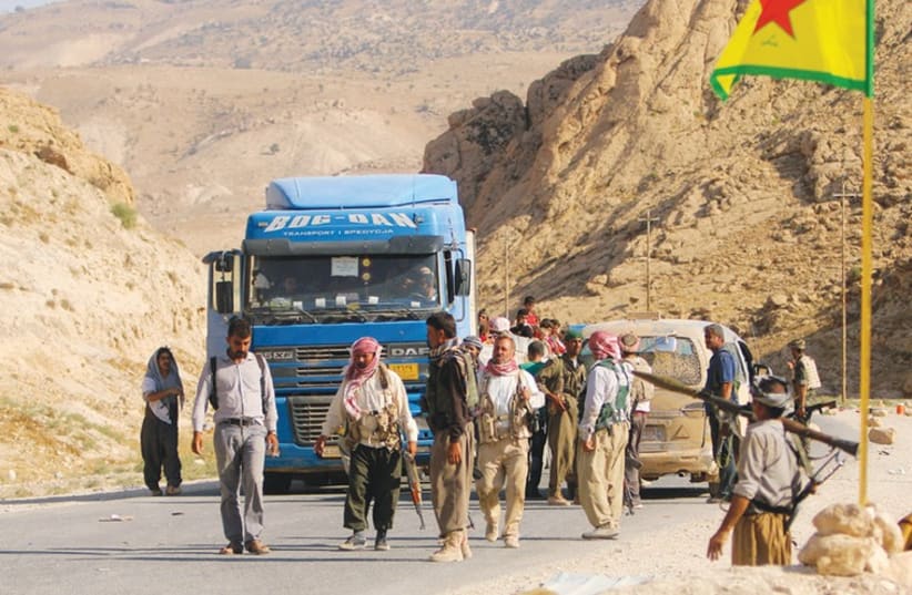 YAZIDI FIGHTERS secure a road on Mount Sinjar on Wednesday that their displaced brethren use to escape to Newrooz camp in Syria’s Hasakah province. (photo credit: REUTERS)