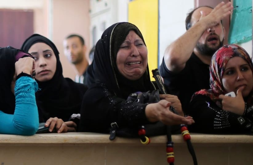 A Palestinian woman, hoping to cross into Egypt, cries as she waits with others at the Rafah crossing between Egypt and the southern Gaza Strip, August 12, 2014. (photo credit: REUTERS)