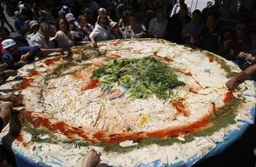 People stand around a large plate of hummus in Jerusalem, May 5, 2008. (photo credit: REUTERS)