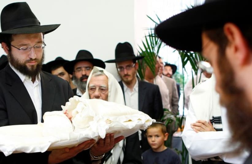 A rabbi holds an eight-day-old baby during a circumcision ceremony in Brussels, August 20, 2009. (photo credit: REUTERS)