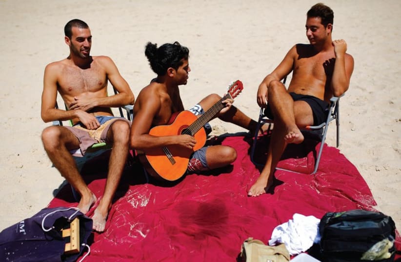 Sun-tanned Israelis relax on a beach near Tel Aviv. (photo credit: REUTERS)