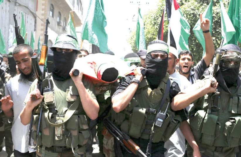 Hamas militants bury a slain comrade in Gaza (photo credit: IBRAHEEM ABU MUSTAFA / REUTERS)