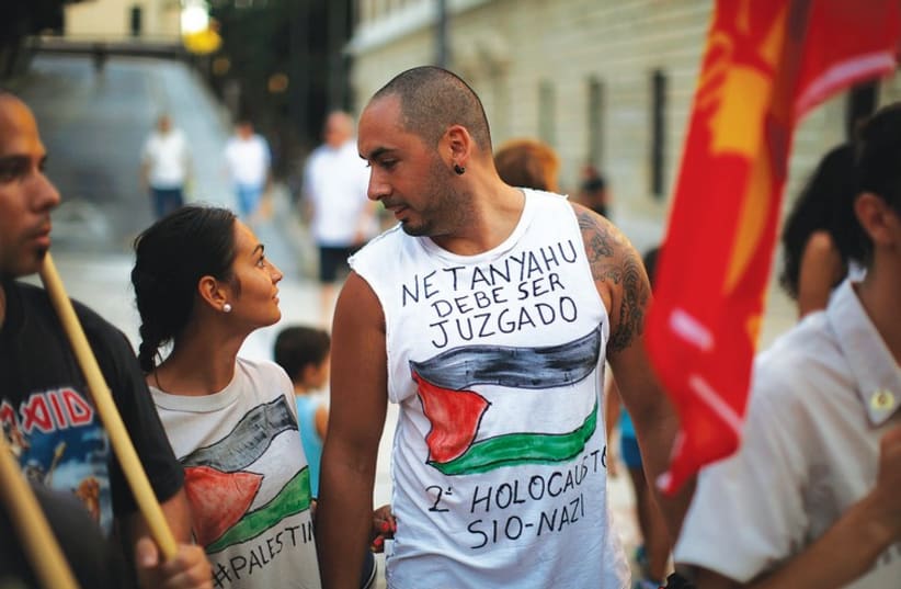 PEOPLE TAKE part in a protest against Israel in Malaga, Spain, on August 8. The words on the shirt read ‘Netanyahu must be judged. Second Zionist-Nazi Holocaust.’ (photo credit: REUTERS)