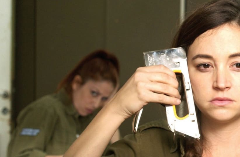 Daffi, a bored and disgruntled IDF clerk, played by Nelly Tagar, contemplates putting an end to it all with a stapler in ‘Zero Motivation (photo credit: YARON SHCARF)