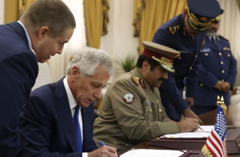 US Secretary of Defense Chuck Hagel, left, and Qatari Defense Minister Hamad bin Ali al-Attiyah sign a Defense Cooperation Agreement in Doha Dec. 10, 2013. (photo credit: REUTERS)