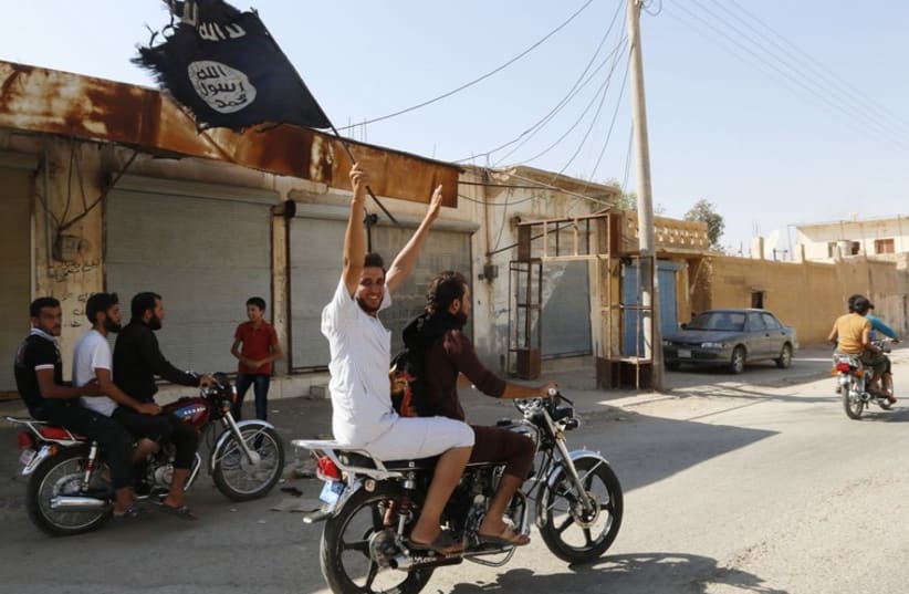 Syrian waves an Islamist flag in celebration after Islamic State militants took over Tabqa air base (photo credit: REUTERS)