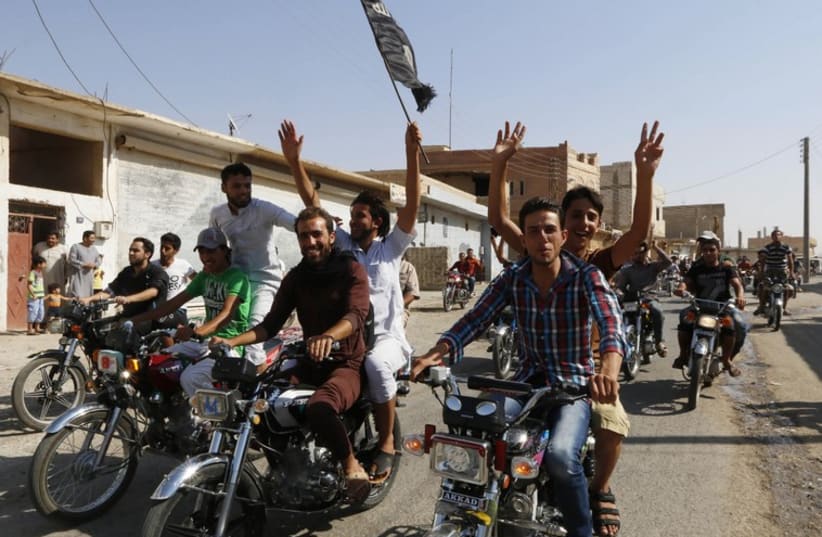 Residents of Tabqa city tour the streets on motorcycles, carrying flags in celebration after Tabqa air base fell to Islamic State (photo credit: REUTERS)