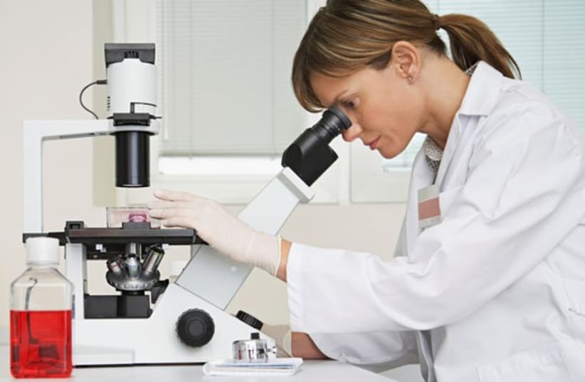 A scientist looks through a microscope (photo credit: INGIMAGE)
